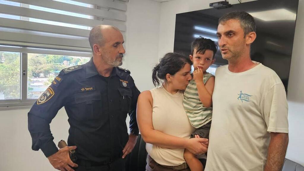 Юваль с мамой и папой в полицейском отделении (Фото: полиция) הילד יובל קוגן שנעדר ליממה שלמה בחוף באשקלון ואותר בניצנים עם מפכ"ל המשטרה דני לוי והוריו