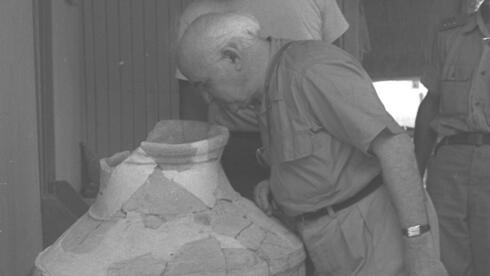 תמונה מ-1958: ראש ממשלת ישראל דוד בן-גוריון בעת ביקורו בחפירות חצור, מסתכל לתוך פיטס (כלי אגירה גדול) שהתגלה בחפירה. מאחוריו יגאל ידין