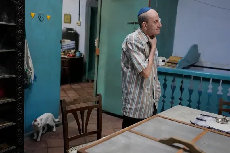 Keith Hallegua, a Paradesi Jew, stands next to his dining table as his cat walks past at his home in the historic Jew Town neighborhood (Photo: AP Photo/Aijaz Rahi) Keith Hallegua, a Paradesi Jew, stands next to his dining table as his cat walks past at his home in the historic Jew Town neighborhood