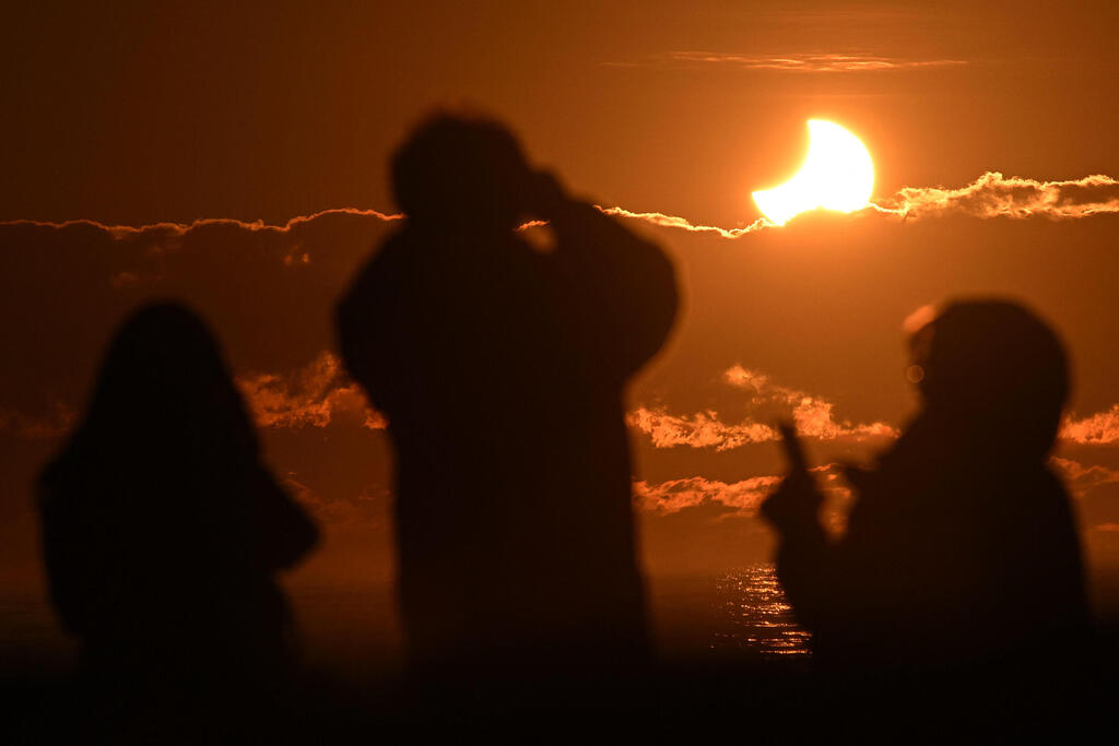 Photo: Sanka Vidanagama/AFP אנשים צופים בליקוי חמה חלקי