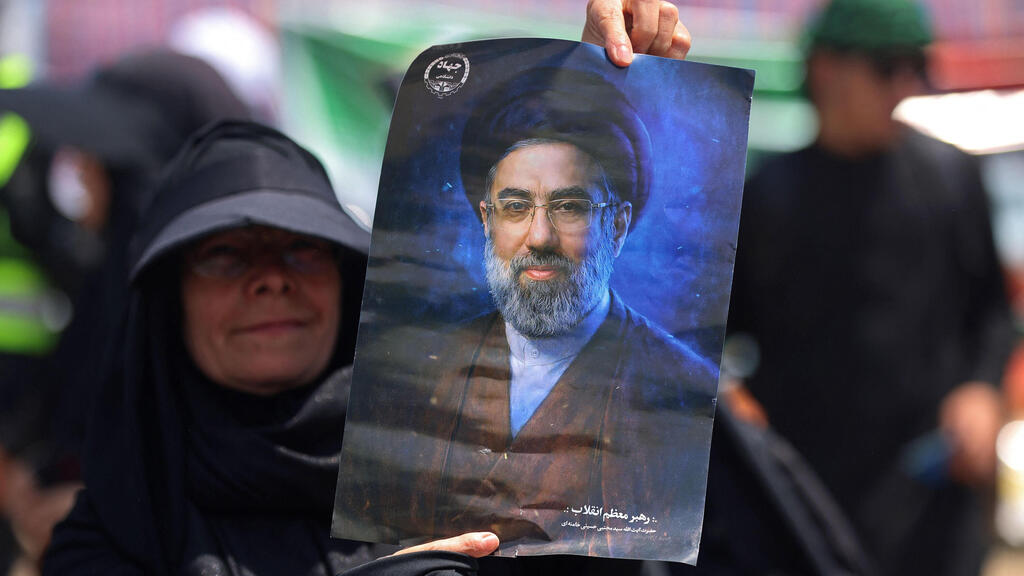 زنی تصویر مجتبی خامنه‌ای را حمل می‌کند