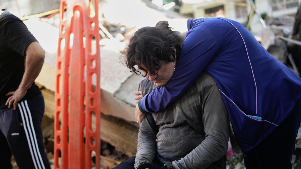 Жители города Кали (Фото: AP Photo/Ivan Valencia) קולומביה רעידת אדמה רעש הריסות קאלי שכנים מתחבקים בזמן שהמחלצים מחפשים
