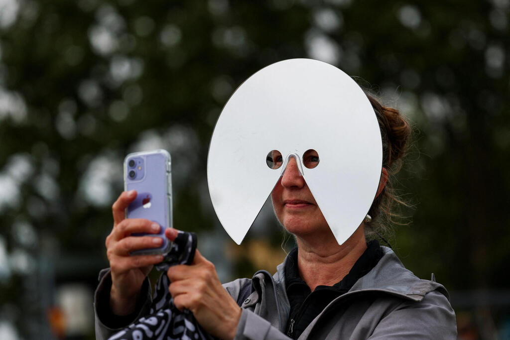 A woman watches the solar eclipse in Reykjavik (Photo: Denis Balibouse/Reuters) אישה צופה בליקוי החמה ברייקיאוויק