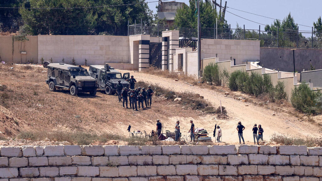 IDF forces alongside Jewish Israelis in front of Palestinian homes in the village of Qusra (Photo: Zain Jaafar / AFP) כוחות צה"ל לצד מתנחלים מול בתי פלסטינים בכפר קוסרה