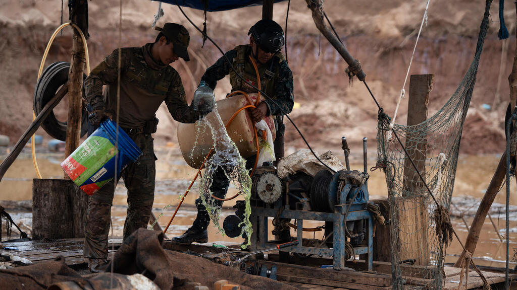 Pouring gasoline on gold mining equipment before setting it alight (Photo: Guadalupe Pardo/AP) חיילי חיל הים הפרואני שופכים דלק על ציוד כרייה כדי להעלות אותו באש ולהשמיד אותו