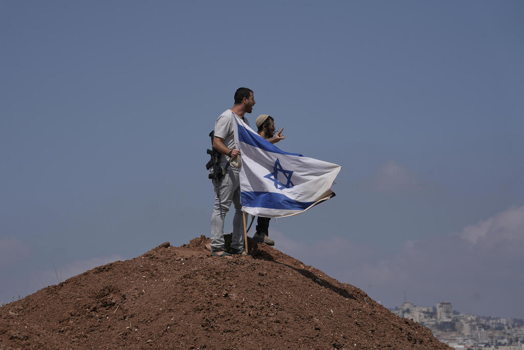 Settlers on a hill near Beit Sahour with an Israeli flag (Photo: AP Photo/Mahmoud Illean) ליד בית סאחור מתנחלים על גבעה עם דגל ישראל