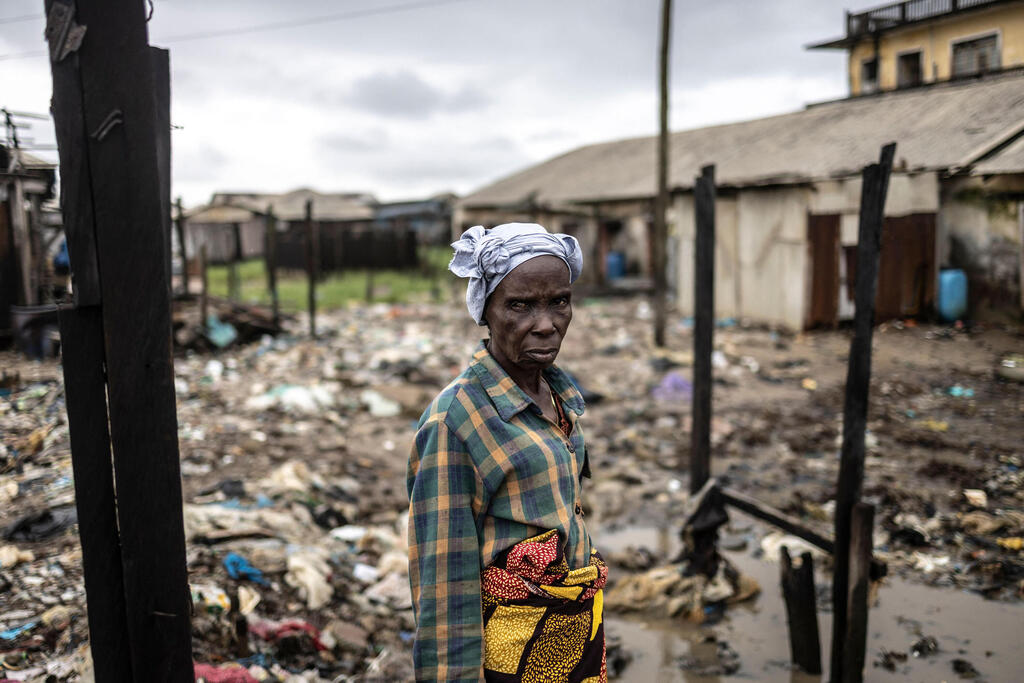 A resident of Ayetoro, Nigeria, stands against the backdrop of homes destroyed by rising Atlantic Ocean levels (Photo: Olympia de Maismont/AFP) תושבת אייטורו בניגריה, על רקע הבתים שנהרסו בגלל עליית פני האוקיינוס האטלנטי