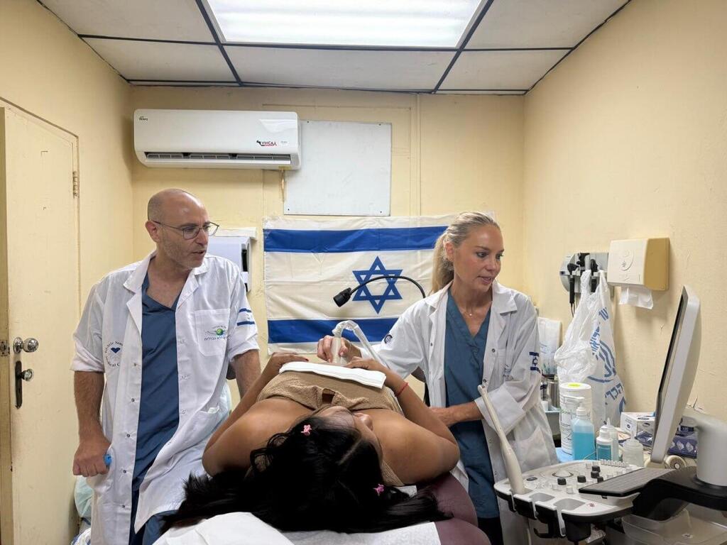 Photo: Israeli Embassy in Panama הבן הפארמדיק עידו בודק לחץ דם לאשת הנשיא בעוד האם ד"ר רונית אלמוג, צופה בגאווה