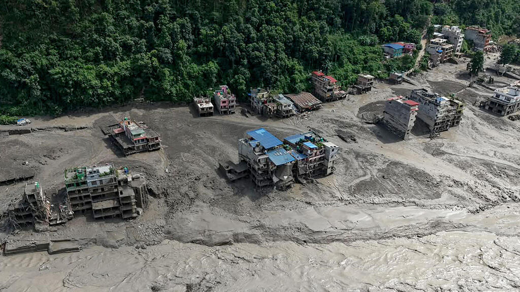 Houses lie partially submerged in muddy water along a riverside after flash floods at Trishuli Bazar in Nepal's Nuwakot district 