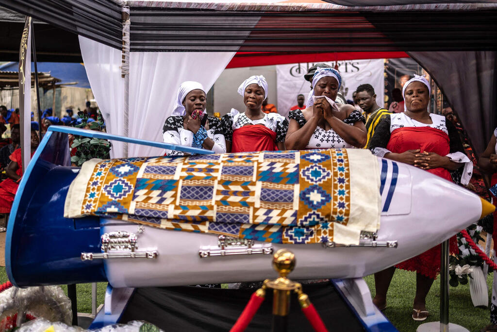 The pen-shaped coffin at the funeral of the teacher, who spent more than 50 years in education (Photo: Olympia de Maismont/AFP) גאנה ארונות קבורה מיוחדים קרובי משפחה לצד ארון קבורה בצורת עט המוכתם בדם כבשים של המורה הגנאי המנוח סמואל קומי טטה ב הלווייתו