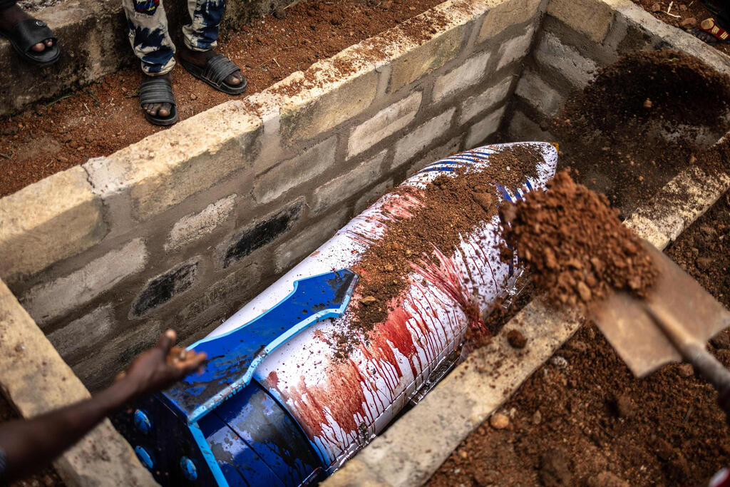 The giant pen is lowered into Tetteh’s grave (Photo: Olympia de Maismont/AFP) גאנה ארונות קבורה מיוחדים ארון קבורה בצורת עט המוכתם בדם כבשים של המורה הגנאי המנוח סמואל קומי טטה ב הלווייתו מונח בקבר