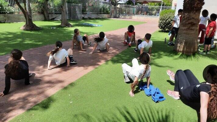 Unpleasant to sit on synthetic grass (Photo: Courtesy of Adam Teva v'Din) ילדים על דשא סינתטי