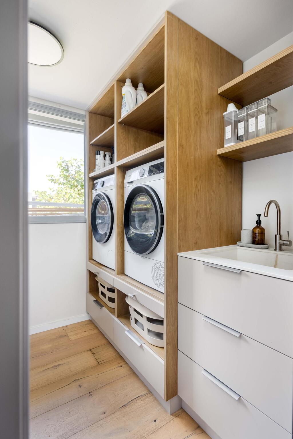 A practical laundry room with a washer and dryer positioned to avoid the need to bend down (Photo: Orit Arnon) בית דו-משפחתי ברמת גן, עיצוב: שרונה טביב