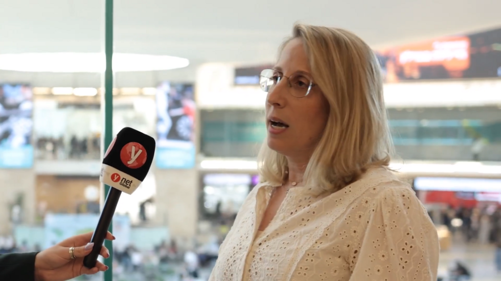 Revital Ackerman waits for new olim at Ben Gurion Airport (Photo: Screenshot) Revital Ackerman waits for new olim at Ben Gurion Airport