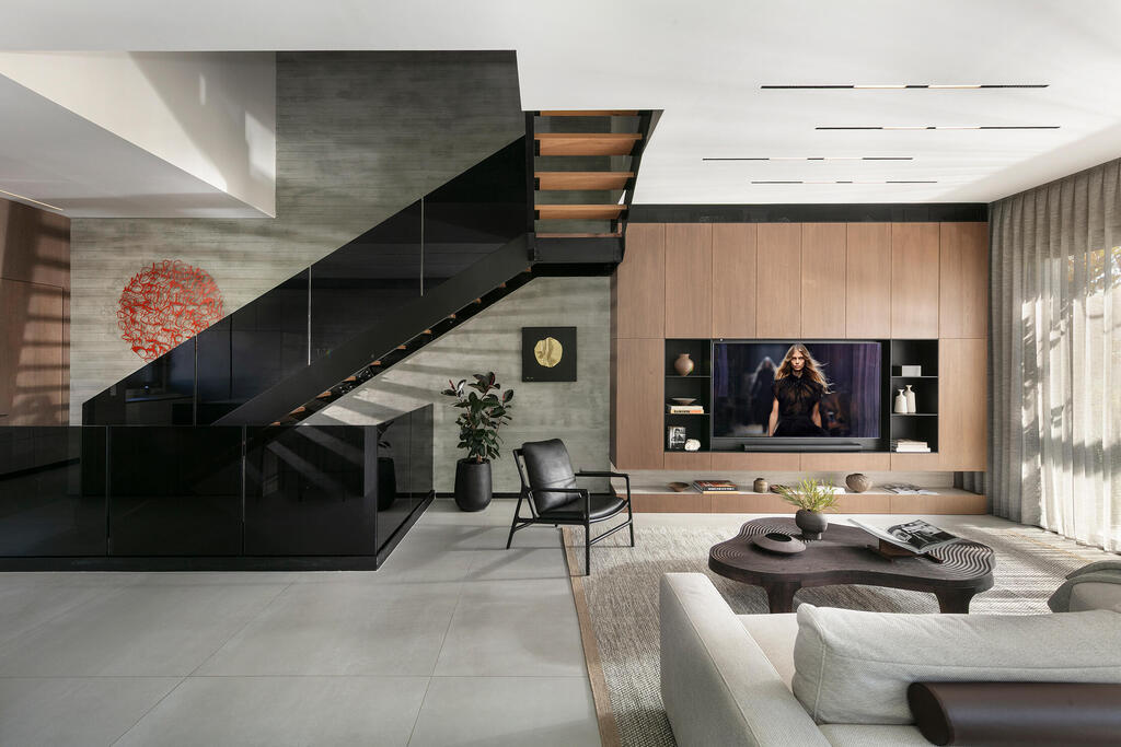 The living room, staircase and basketball-inspired artwork reflecting the couple’s shared interest (Photo: Elad Gonen) בית פרטי באבן יהודה, עיצוב פנים: ליעד יוסף