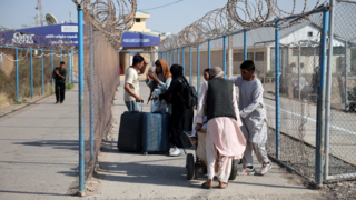 Afghan nationals carrying their belongings walk after crossing the border from Iran at the Islam Qala border crossing in Herat province, Afghanistan 