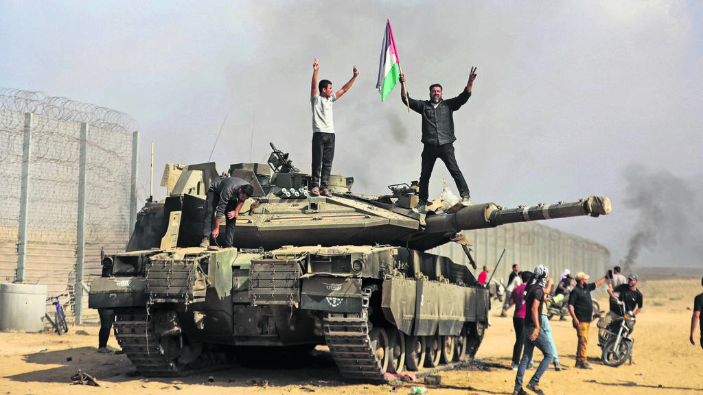 Hamas terrorists on an IDF tank near the Gaza border, Oct. 7, 2023 (Photo: Yousef Masoud/AP) מחבלי חמאס על טנק של צה"ל בעוטף, 7 באוקטובר 2023