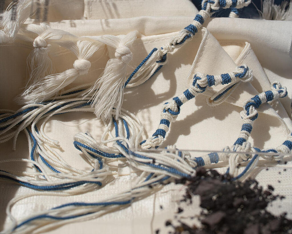 Dried pigment and a tallit with tassels in white and light blue (Photo: Courtesy of Ptil Tekhelet, Jenny Katzner) פיגמנט מיובש וטלית עם ציציות בצבעי לבן ותכלת