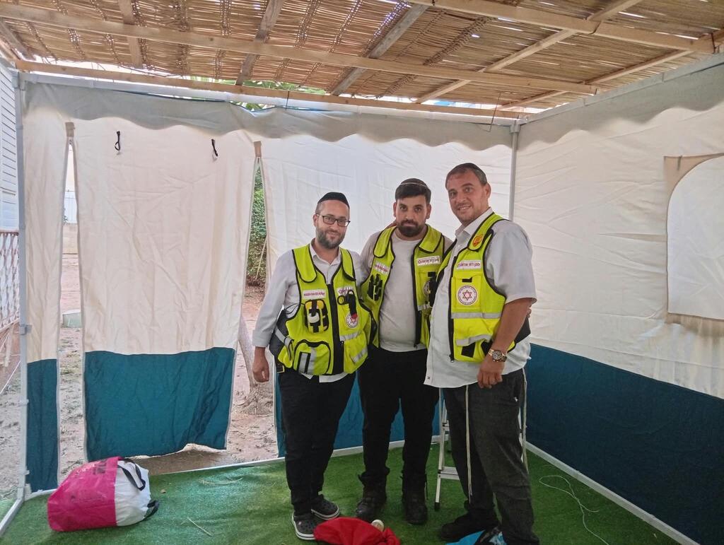 MDA medics pose inside the completed sukkah after treating a woman injured while building it in Netanya (Photo: Magen David Adom) MDA medics pose inside the completed sukkah after treating a woman injured while building it in Netanya