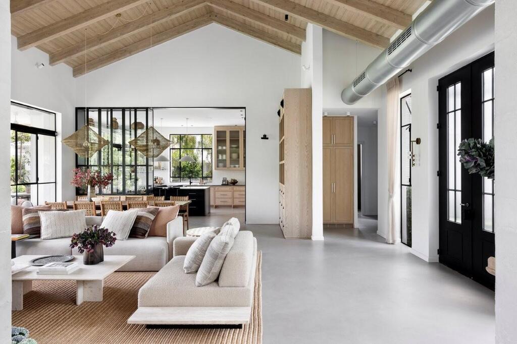 The open-plan living area features a soaring pitched ceiling, exposed ductwork and black-framed doors (Photo: Itay Benit) The open-plan living area features a soaring pitched ceiling, exposed ductwork and black-framed doors