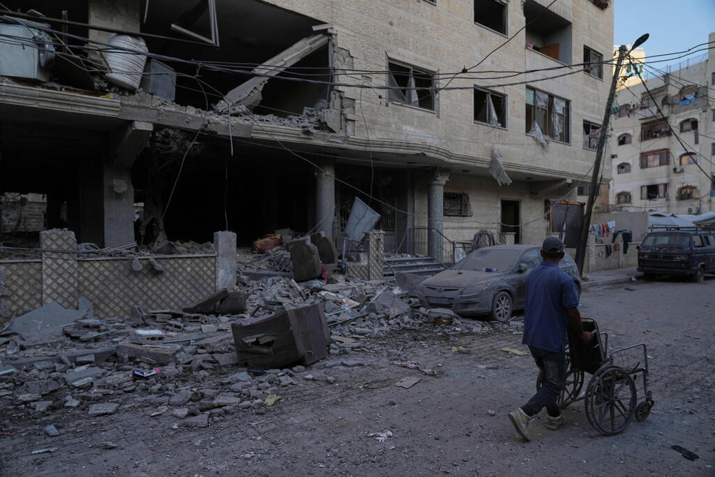 Palestinians walk near the wreckage of destroyed buildings in Gaza City (Photo: AP Photo/Jehad Alshrafi) העיר עזה