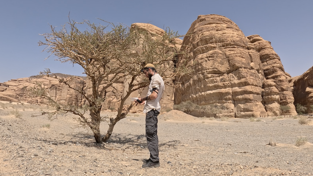 Adam putting on tefillin in the field (Photo: Courtesy of Adam Jano) אדם מניח תפילין בשטח