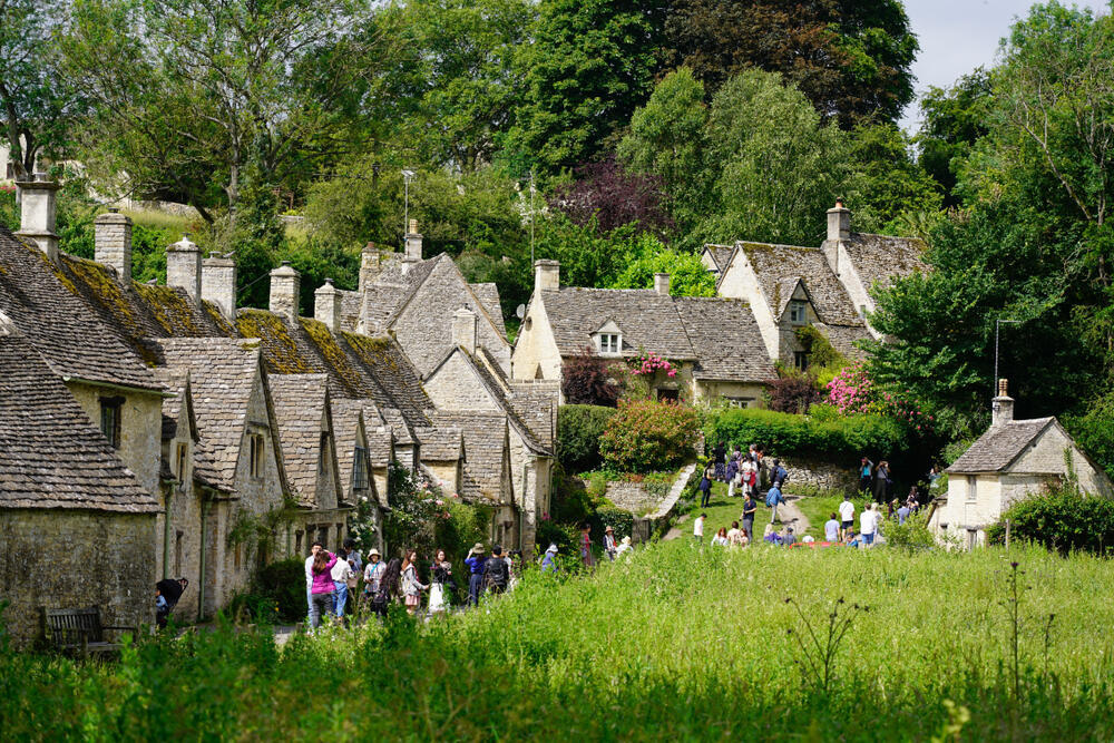 Tourists stroll among the traditional stone houses in the picturesque village of Bibury (Photo: Wang Sing / shutterstock) תיירים מסיירים בין בתי האבן המסורתיים בכפר הציורי ביבורי