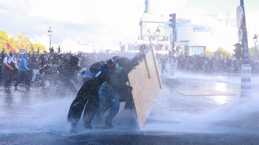 Protesters use wooden boards to shield themselves from water cannon during clashes at Place de la Bastille in Paris (Photo: Kenzo TRIBOUILLARD / AFP) הפגנה פריז כיכר הבסטיליה מחאת תלמידים צרפת