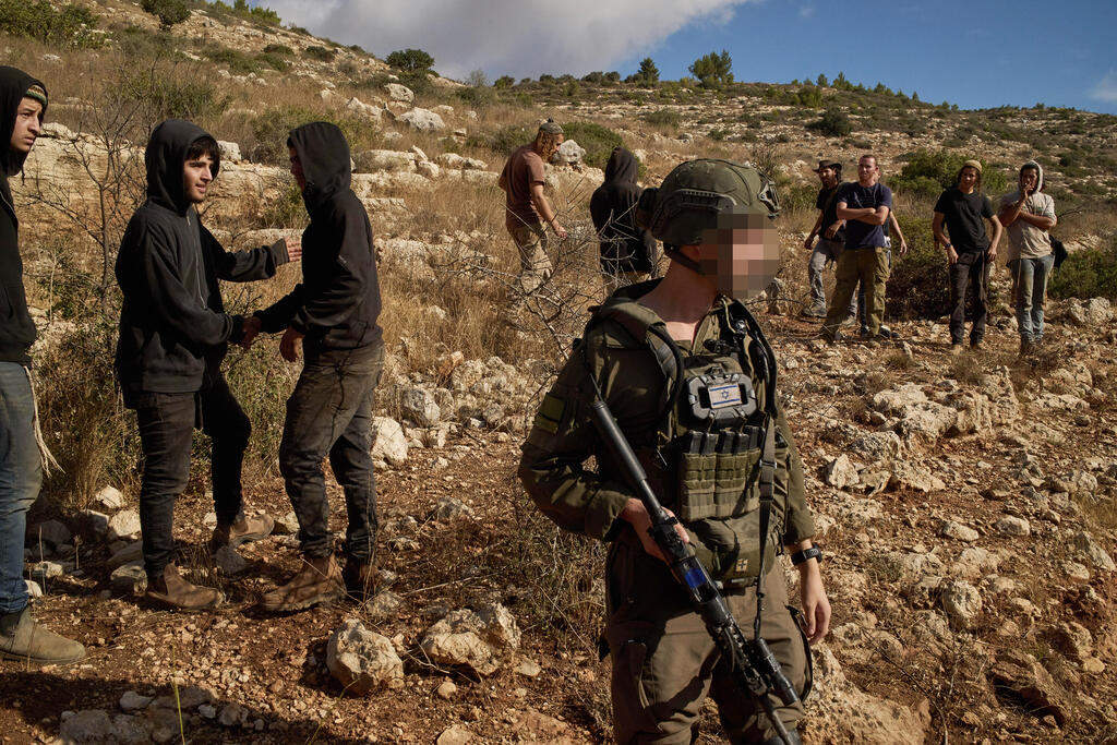 IDF soldiers and Israeli settlers near an olive harvest in the West Bank village of Deir Abu Mash'al (Photo: AP Photo/Leo Correa) דיר אבו משעל