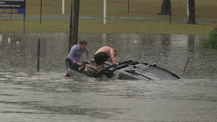 Murray and a bystander pull the trapped driver from the vehicle (Photo: Reuters) כתב באוסטרליה קפץ למים כדי להציל נהג שנתקע בהצפות