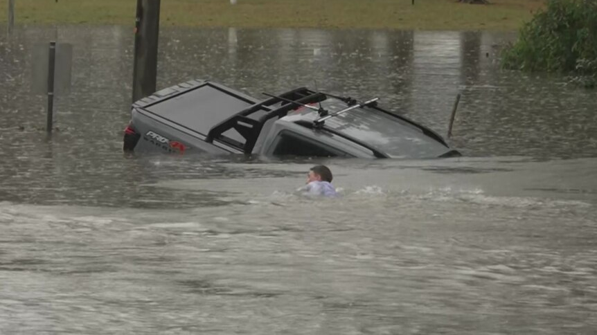 ABC reporter Will Murray swims toward the sinking vehicle (Photo: Reuters) כתב באוסטרליה קפץ למים כדי להציל נהג שנתקע בהצפות
