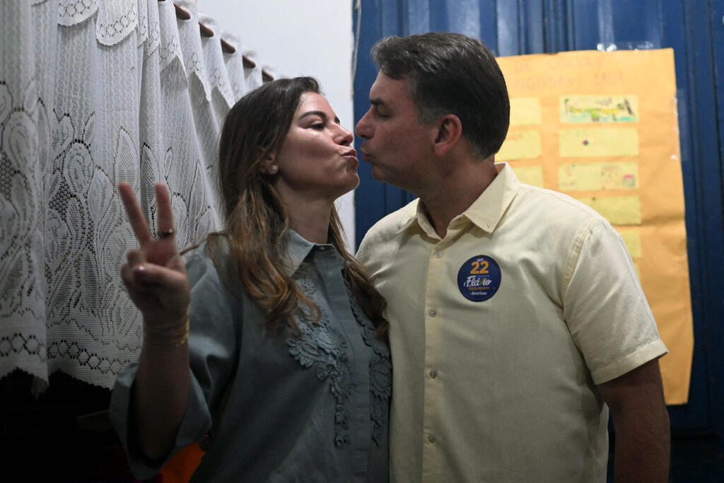 Bolsonaro kisses his wife, Fernanda, at a polling station in Rio de Janeiro on Sunday (Photo: MAURO PIMENTEL / AFP) פלאביו בולסונרו מועמד הימין לנשיאות ב בחירות ב ברזיל עם אשתו פרננדה בקלפי בריו דה ז'ניירו