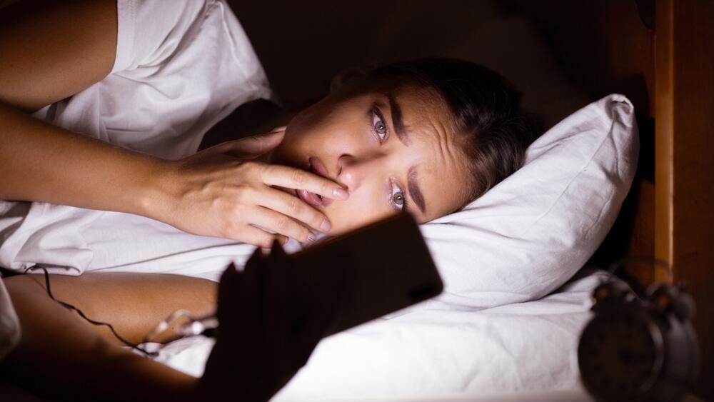 Using a smartphone in bed. Repeated exposure to election coverage can reinforce feelings of threat (Photo: Shutterstock) שימוש בטלפון נייד במיטה