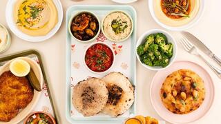 A selection of Israeli-inspired dishes at Safta's Table in New Orleans, including hummus, pita, schnitzel and vegetable sides 