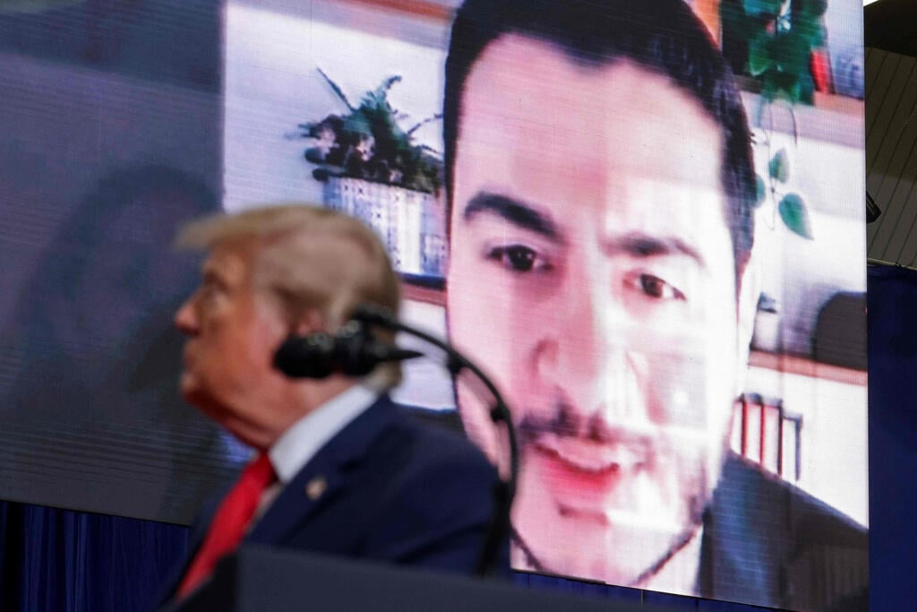 A video of Michigan Democratic Senate candidate Abdul El-Sayed is displayed behind U.S. President Donald Trump as he delivers remarks during an election rally in Port Huron, Michigan 