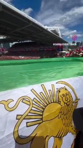 Iranian fans wave the Lion and Sun flag in the stadium.