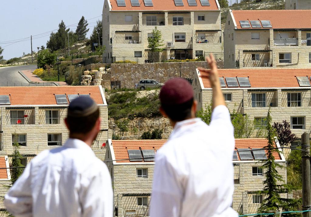 Two Jewish men standing in front of the West Bank settlement of Ofra 