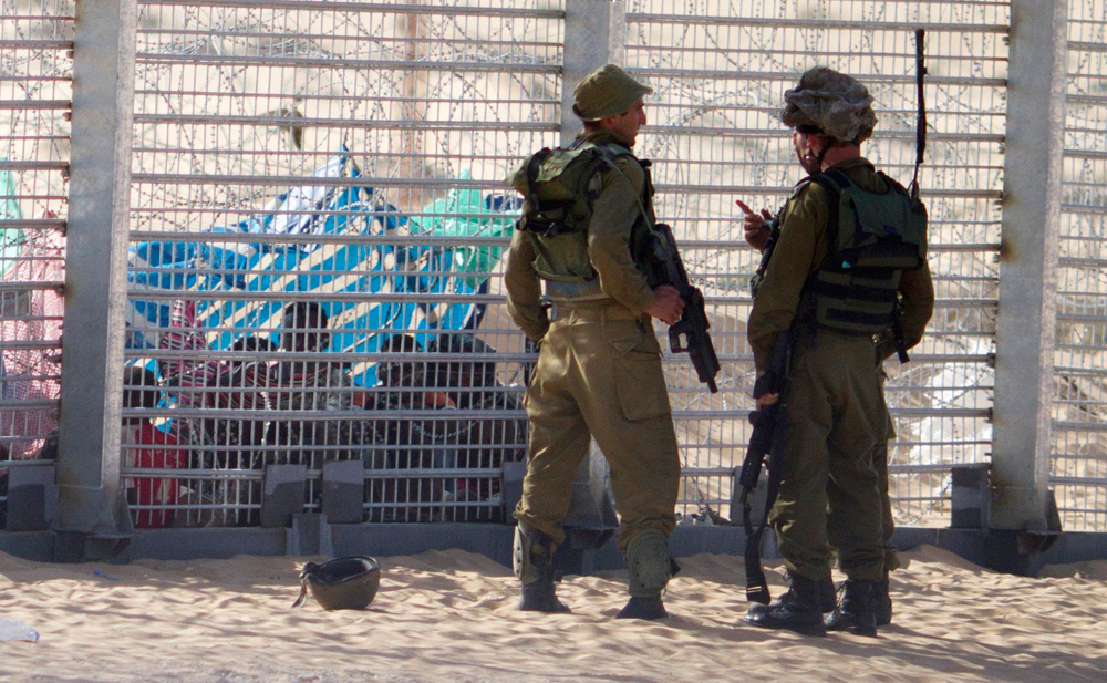 IDF troops watch asylum seekers on the Egyptian side of the border with Israel 