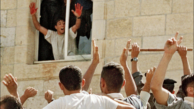 A Palestinian stands in the window of a Ramallah police station in October 2000, displaying the blood of two slain Israeli soldiers on his hands 