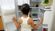 ילדה מתבוננת לתוך מקרר כמעט ריק