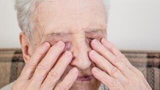 אישה עיוורת שמה ידיים על העיניים