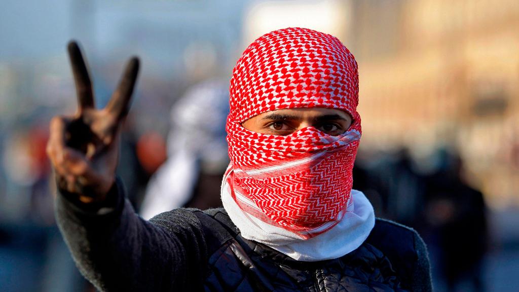 A protester in Najaf flashes the victory sign (Photo: AP) נג'ף הפגנות מהומות מחאה עיראק
