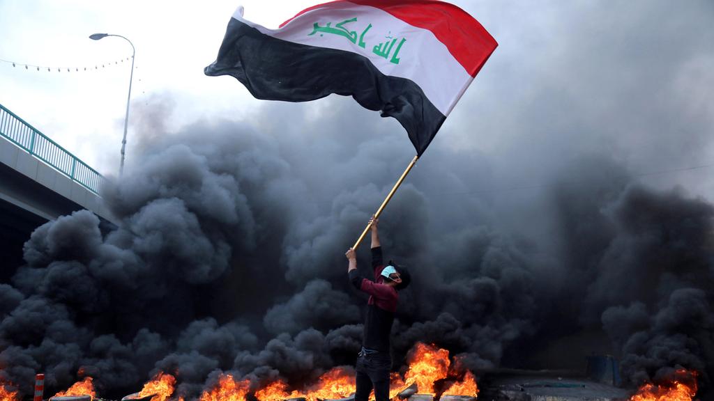 An Iraqi protester waves the national flag (Photo: Reuters) כרבלא הפגנות מהומות מחאה עיראק