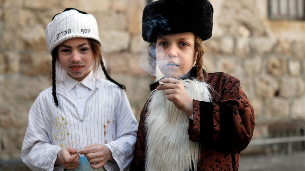 Illustrative: Boys smoke a cigarette in one of Jerusalem’s ultra-Orthodox neighborhoods during the Purim festival, March 2018