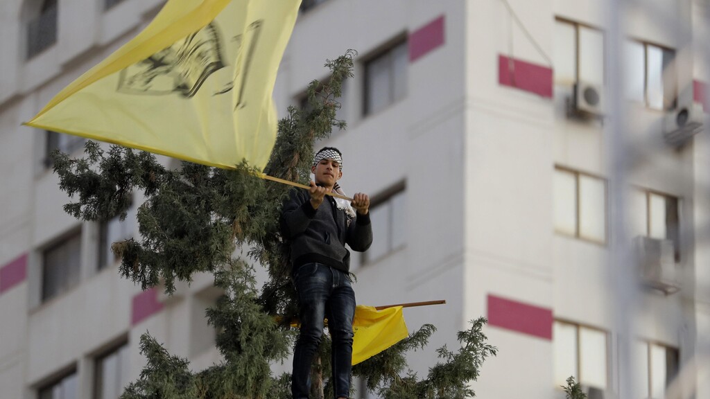 A Palestinian supporter waves a yellow Fatah flag during a celebration marking the 55th anniversary of the Fatah movement in Gaza City, Dec. 31, 2019