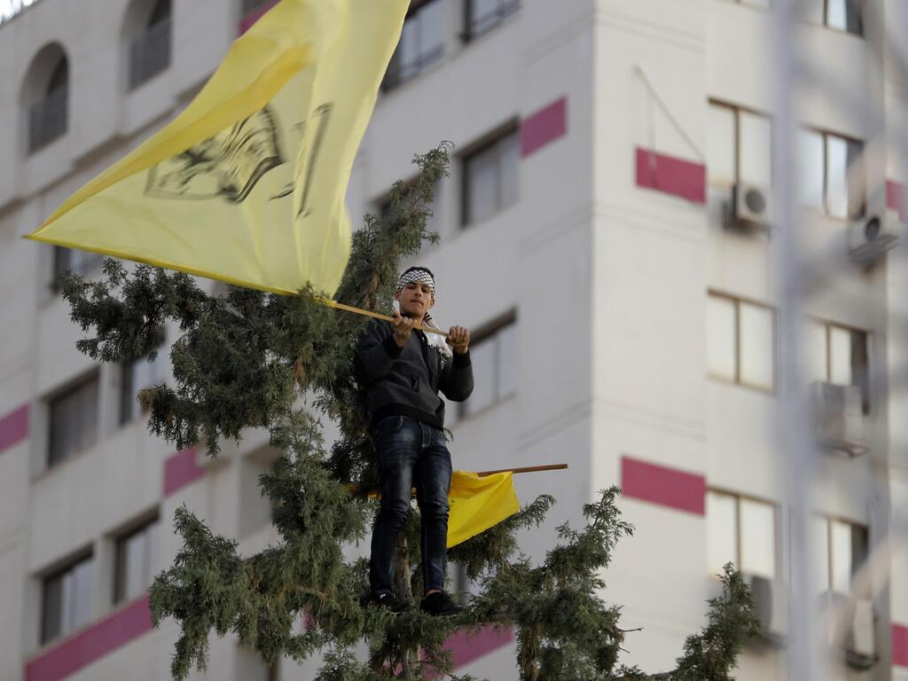 A Palestinian supporter waves a yellow Fatah flag during a celebration marking the 55th anniversary of the Fatah movement in Gaza City, Dec. 31, 2019