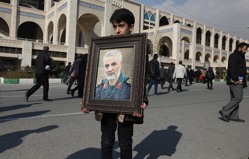 A young Iranian in Tehran holds a photo of assassinated general Qassem Soleimani 