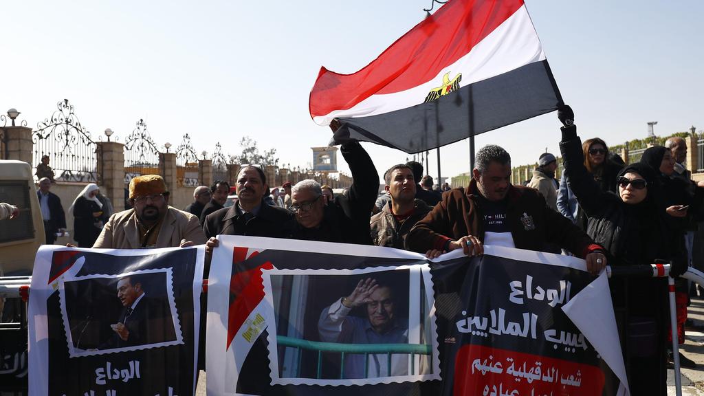 Supporters of Hosni Mubarak hold placards praising the former Egyptian president outside the mosque east of Cairo where his funeral will be held, Feb. 26, 2020 