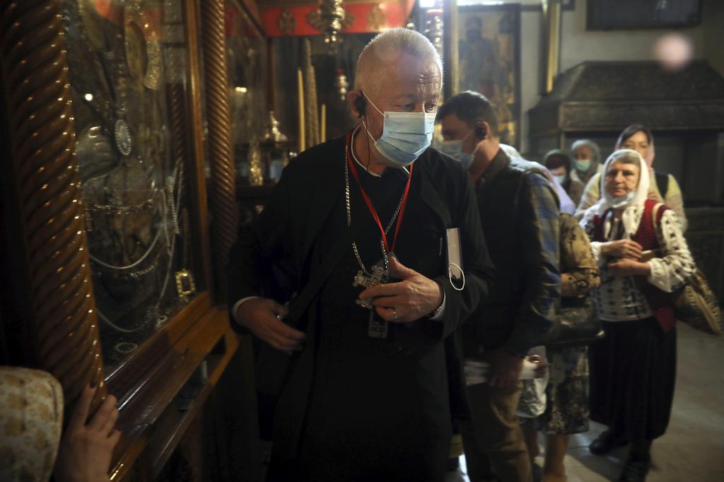 A priest and visitors wear masks at the Church of the Nativity in Bethlehem after a suspected coronavirus outbreak in the city, March 5, 2020 