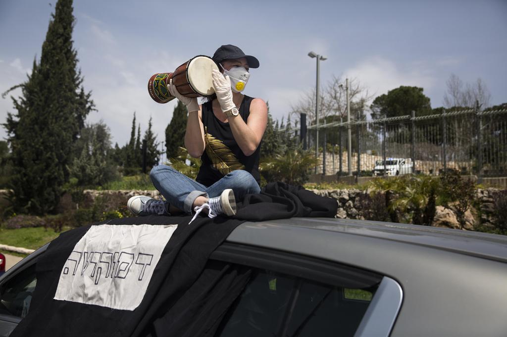 An Israeli woman wearing mask and gloves against coronavirus protests the suspension of the Knesset in Jerusalem last month. The sign reads: 'Democracy' (Photo: Getty Images) מחאת הדגלים השחורים בכנסת : "מצילים את הדמוקרטיה"